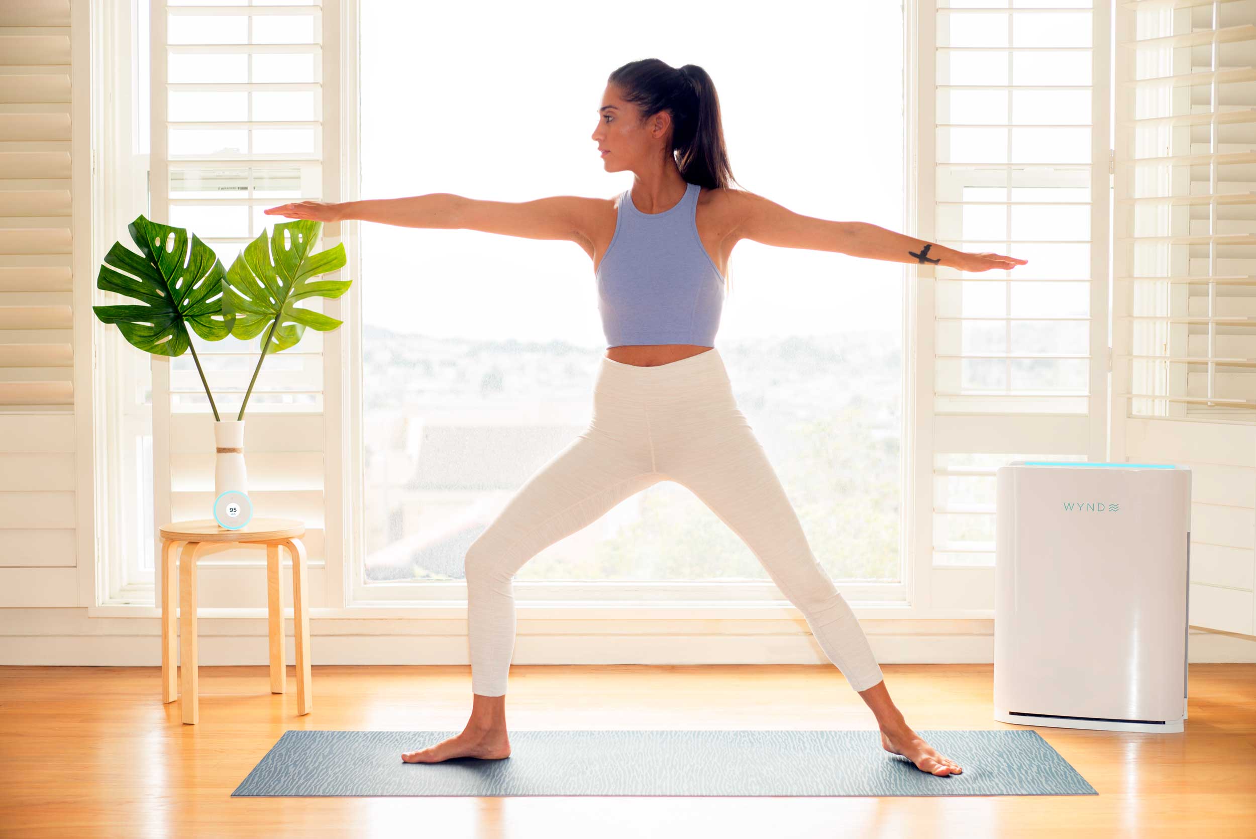 Photo of the Wynd Halo and Wynd Home Purifier in a woman's house as she does yoga